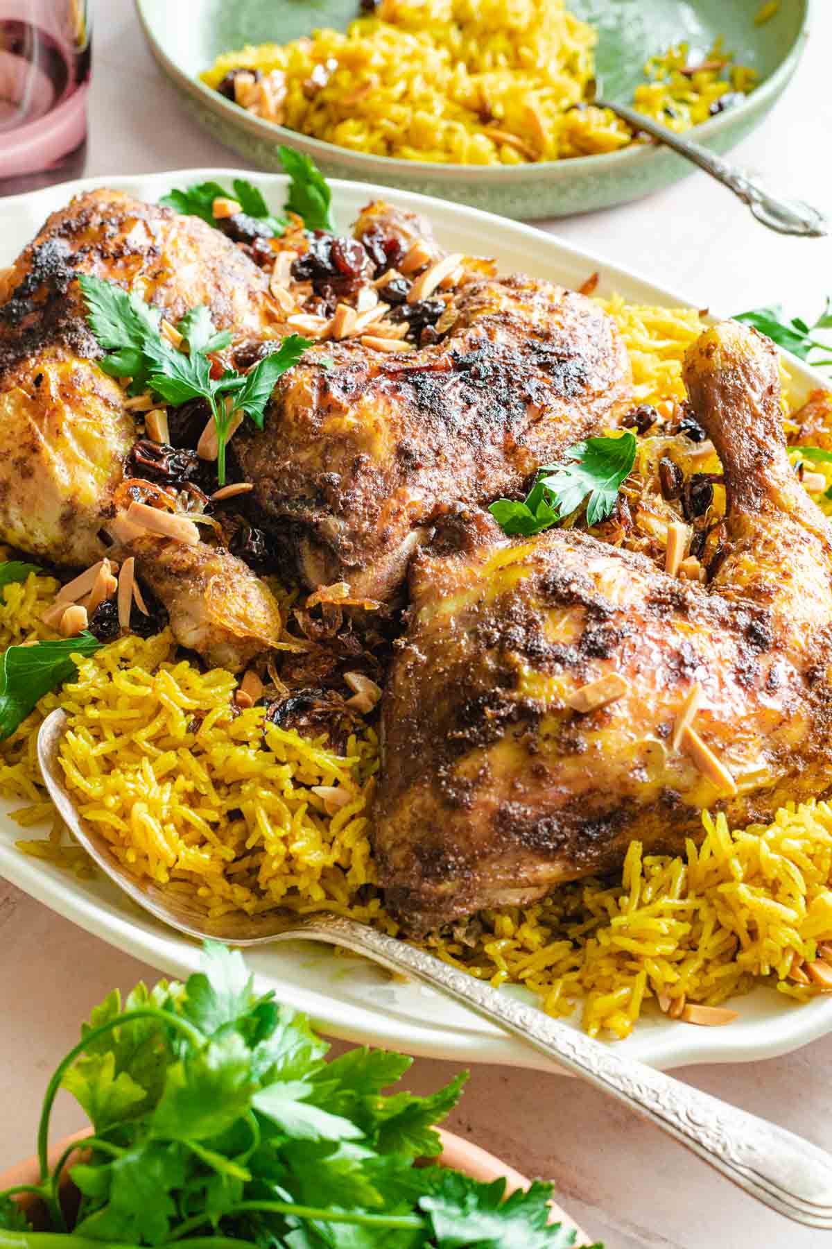 chicken mandi served on a platter of spiced rice with raisins and almonds