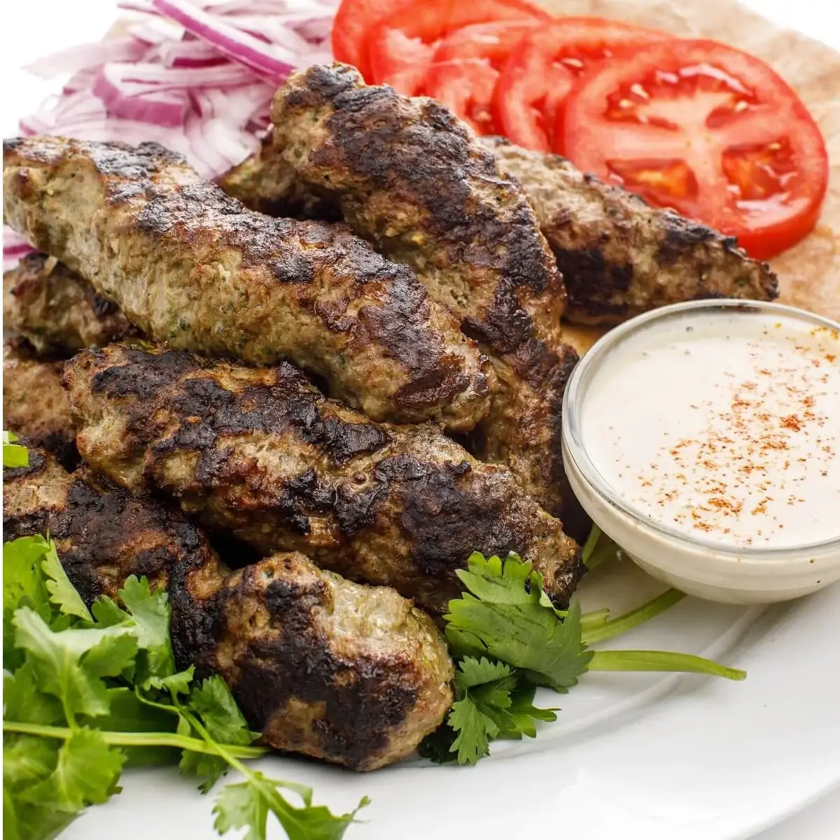 Lebanese kafta kebabs grilled on skewers with tahini sauce and pita