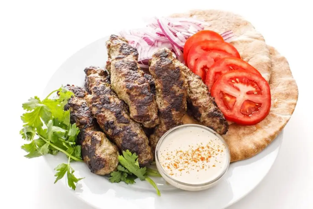 Lebanese kafta kebabs grilled on skewers with tahini sauce and pita