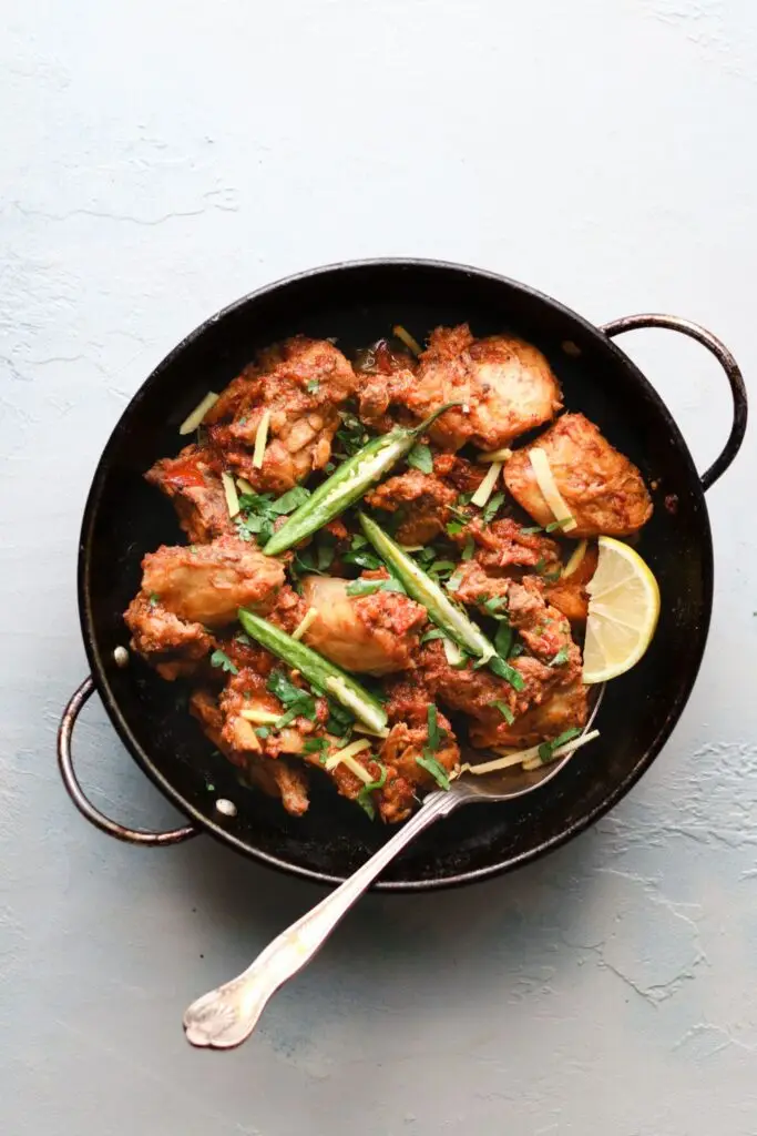 chicken karahi in a wok-style pan with ginger and green chilies